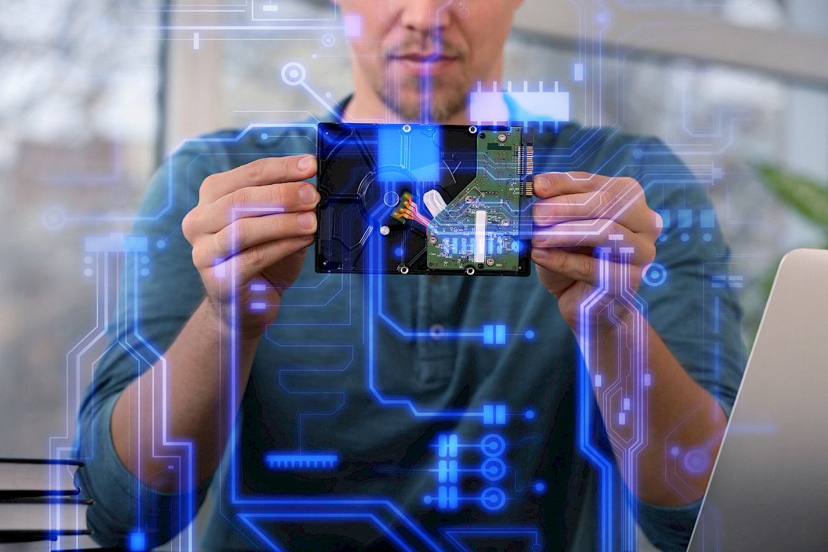 Mann h&auml;lt eine Platine vor leuchtenden digitalen Schaltkreisen