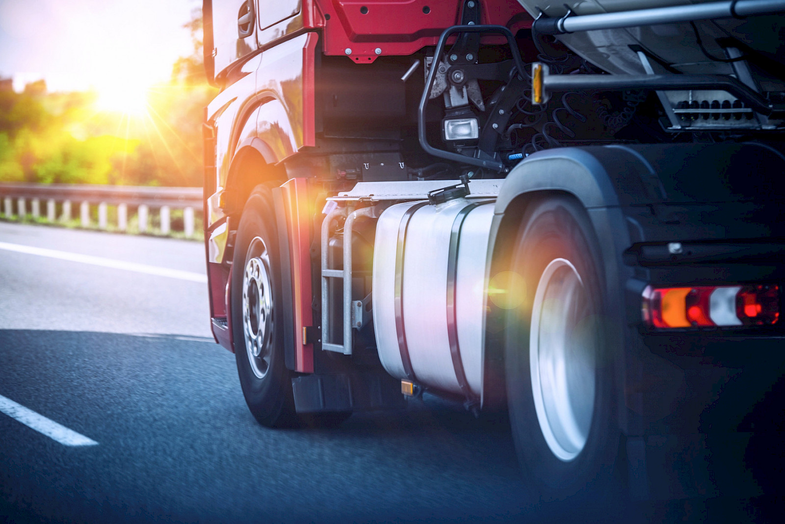 Roter Sattelzug fährt bei Sonnenuntergang auf der Autobahn